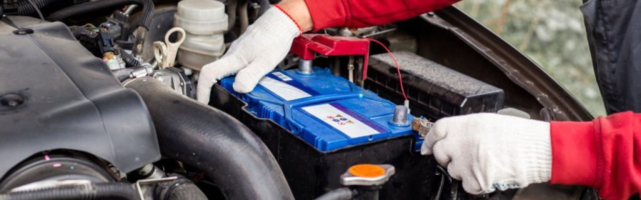 a car mechanic installs a battery in a car. Battery replacement and repair.